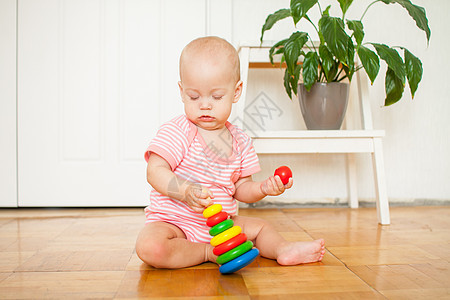小女孩坐在地板上爬行 玩着色彩鲜艳的益智玩具情绪化教育儿童苗圃幸福孩子快乐闲暇金字塔婴儿图片
