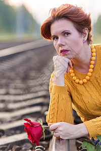 穿着红玫瑰坐在铁路的铁轨上 美丽女人的肖像图片