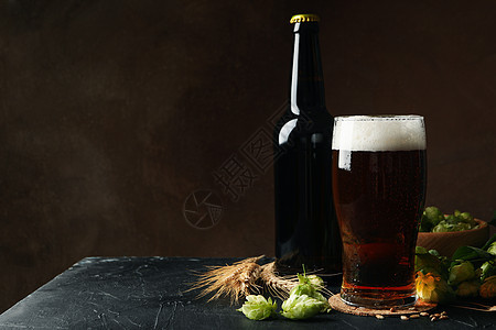 棕色背景的啤酒 跳和小麦黑色泡沫啤酒厂派对玻璃杯子酒精酒吧食物瓶子图片