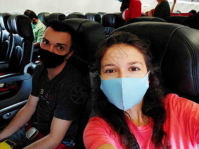 机舱内 一对戴着口罩的旅客 根据冠状病毒大流行的新规则飞行图片