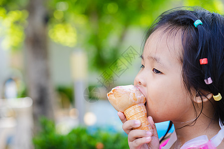 亚洲小女孩吃冰淇淋室外 与自然相邻的冰淇淋喜悦女孩孩子奶油头发眼睛微笑绿色乐趣儿童图片