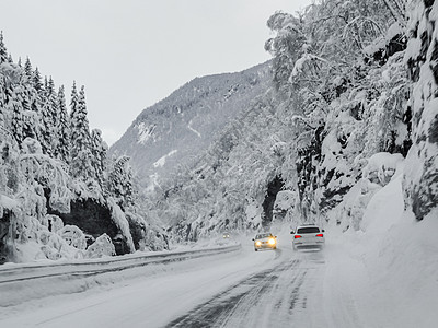 在挪威的雪路和风景中行驶小路运输暴风雪季节乡村森林旅行交通天气国家图片