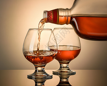 白兰地是用瓶子倒的酒吧棕色庆典饮料酒杯奢华反射白色液体红色图片