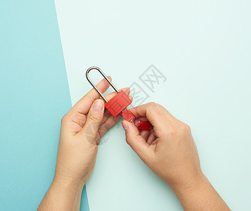 蓝色背景的有钥匙在女性手中的金属锁手指安全红色棕榈房子手臂女士图片