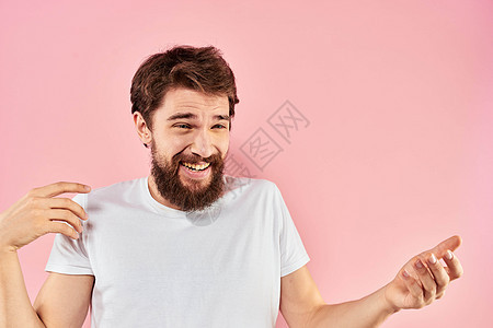 身穿白色T恤衫的胡子男子手举双手 面部表情贴近粉红色背景男性商业情绪化男人学生工作室成人快乐微笑衬衫图片