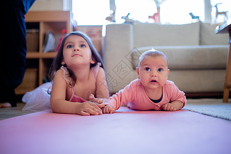 小女孩躺在她的小妹妹旁边 在粉红鲁上快乐高清图片素材