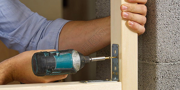 手工艺人持有便携式螺丝刀 用于修理金属角 在木板上搞螺丝工作力量建筑工匠硬木工艺乐器承包商领带角落图片