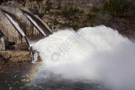 俄罗斯马加丹地区的科雷马水电站 从水力发电站的大坝溢洪道 一条巨大的水流在高山的背景下流入河流阳光海浪活力镜头蓝石薄雾水电溪流技图片