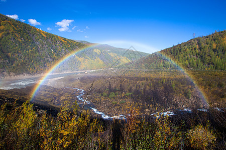 全尺寸美丽明亮的彩虹以秋天的山丘和一条小溪为背景 溢洪道水电彩虹享受光谱幸福天堂天空日光土地折射气候环境背景图片