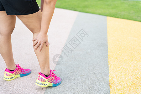 女性胖脚步运动员腿部受伤和疼痛 手抓着痛苦的腿在公园里跑来跑去按摩膝盖十字形小牛女士慢跑者跑步伤害事故训练图片