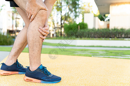 男性运动员腿部受伤和疼痛 手在公园里跑时抓着痛苦的膝盖疾病赛跑者踪迹小牛训练女性治疗慢跑者抽搐伤害图片