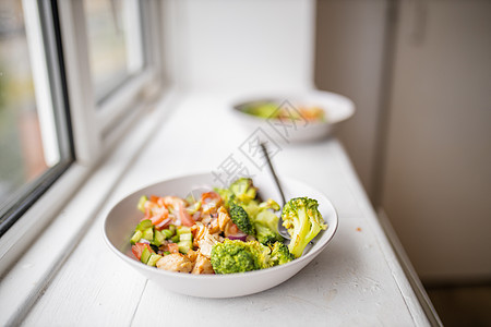 在窗户旁边的白碗上的花椰子和鸡肉沙拉蔬菜洋葱白色绿色饮食盘子营养食物胡椒沙拉图片