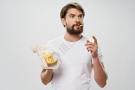 胡子人手里拿着快餐炸薯条吃东西图片