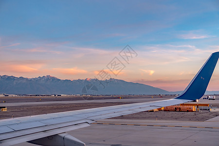 日落时从盐湖城市乘飞机飞越岩石上空山脉翅膀城市地平线飞机图片