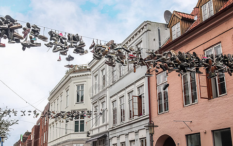 在德国最北边的小镇 名叫弗伦斯堡的老房子之间挂着鞋子建筑金属乐趣运动鞋蓝天细节阳光生活建筑物艺术品图片