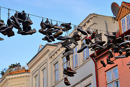 在德国最北边的小镇 名叫弗伦斯堡的老房子之间挂着鞋子旅行旅游细节艺术品蓝色天空蓝天运动鞋阳光街道图片