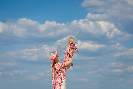 一个穿着浅色夏日太阳裙的迷人女孩和她的小女儿在沙滩上散步 享受温暖阳光明媚的夏日微笑女性孩子情感快乐女士母亲婴儿帽子公园图片