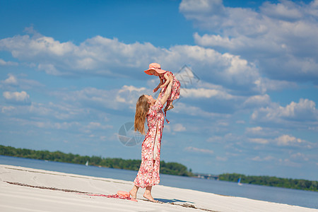 一个穿着浅色夏日太阳裙的迷人女孩和她的小女儿在沙滩上散步 享受温暖阳光明媚的夏日家庭孩子海滩母亲童年裙子公园婴儿妈妈女性图片