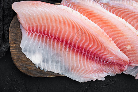 黑底 顶视面的蒂拉皮亚鱼片肉海鲜白鱼粉色图片