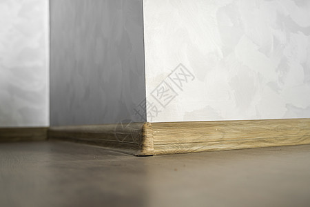 与具有木质纹理的塑料底板层压 家里新安装的强化木地板和踢脚板 现代设计 深色橡木地板镶木地板上塑料底座的特写角落房间住宅压板房子图片
