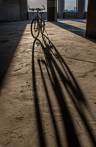 黄色的傍晚阳光穿过停车场的山地自行车车轮冒险运输车道地面日落水泥车辆建筑框架图片