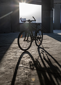 黄色的傍晚阳光穿过停车场的山地自行车车轮日落建筑运输闲暇水泥地面阴影框架车辆图片