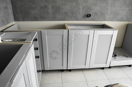 带有家具立面 mdf 的较低定制厨柜安装 灰色模块化厨房由刨花板材料制成 处于不同的安装阶段 框架家具正面是 mdf 型材风俗贮背景图片