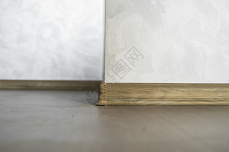 与具有木质纹理的塑料底板层压 家里新安装的强化木地板和踢脚板 现代设计 深色橡木地板镶木地板上塑料底座的特写压板粮食装饰材料硬木图片
