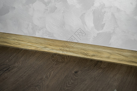 与具有木质纹理的塑料底板层压 家里新安装的强化木地板和踢脚板 现代设计 深色橡木地板镶木地板上塑料底座的特写木板建筑学公寓硬木木图片