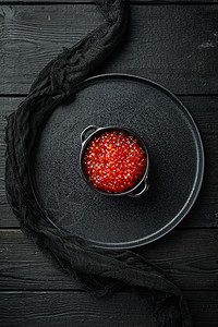黑碗 有美味的红鱼子酱 黑色木制桌底背景 顶楼红色黑木桌子鳟鱼海鲜食物玻璃图片