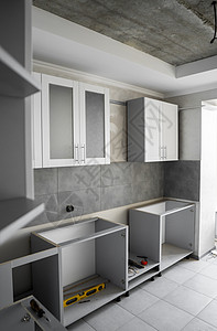 带有白色家具外墙 mdf 的定制厨柜安装 灰色模块化厨房由刨花板材料制成 处于不同的安装阶段 框架家具正面是 mdf 型材硬木服图片