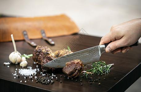将有机烤牛肉卷切在配有成分的木制桌上服务美食木头木板食物雕刻拼盘乡村男人桌子图片