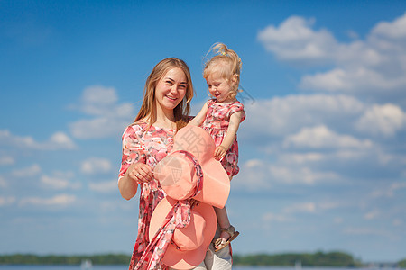 一个穿着浅色夏日太阳裙的迷人女孩和她的小女儿在沙滩上散步 享受温暖阳光明媚的夏日婴儿海滩喜悦天空女士孩子微笑裙子情感妈妈图片