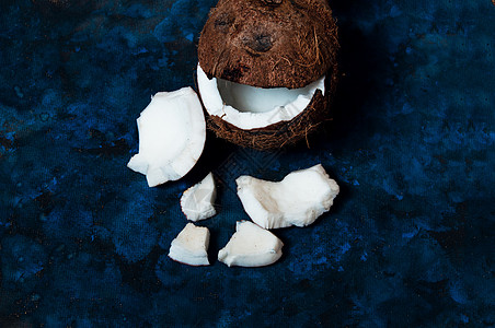 开阔椰子就躺在黑暗的蓝色背景上 旁边是破碎的碎片水果椰子棕榈食物异国药品热带外卖可可饮食图片