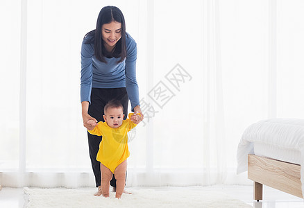 女婴迈出第一步学习和妈妈一起走路家庭帮助母亲孩子女性童年房子卧室父母女儿图片