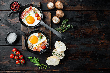 煎蛋配樱桃番茄和面包 用铸铁煎锅做早餐 在旧的深色木桌背景上 顶视图平躺 有文本复制空间图片
