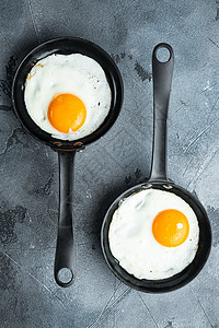 炸鸡蛋加樱桃番茄和面包 早餐用烤铁煎锅煮成的炒饭 在灰色背景下 顶端视野平坦图片