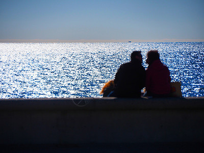 从坐在海边的后面看到无法辨认的拥抱恋人的模糊图像恋爱太阳日落离别情侣旅行海滩幸福夫妻情怀背景图片