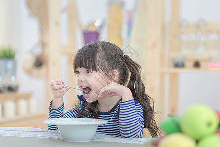可爱的小女孩早上用玉米片和牛奶一起吃早餐 (笑声)图片