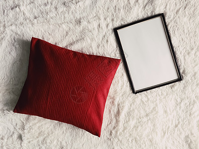红色照片带有空白复制空间的黑色薄木框作为海报照片打印模型 红色垫枕和蓬松的白色毯子 平躺背景和艺术产品家具摄影风格平铺商业织物木头格子羽背景
