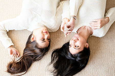 两个最好的朋友躺在地毯上 在家里聊天时说话闲暇女士朋友们牛仔裤微笑成人朋友青年女孩女性图片