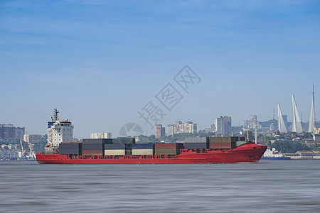 海景与城市景观的背景上的红色集装箱船图片
