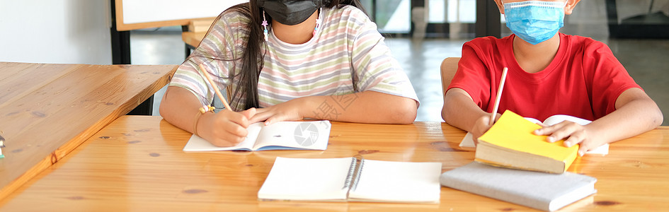 身戴面罩 学习写作作功课笔记的女男学生 在学校进行学习教育女孩口罩孩子们男生家庭作业医疗女学生孩子面具图书馆背景图片