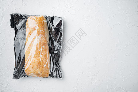 一条新鲜烘焙的工匠全麦 ciabatta 面包装在市场袋子里 白色背景 顶视图平铺 有复制空间和文本空间图片