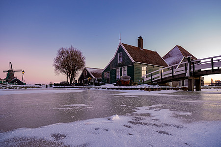 在冬季风车村 雪覆盖了荷兰的木制历史风车荷兰村庄文化房子地标天空农村旅游旅行历史性降雪图片