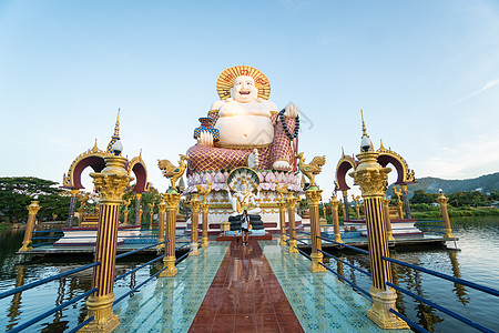 泰国苏梅岛  2020 年 1 月 10 日 在泰国苏梅岛的寺 一个拿着相机的人站在通往一座巨大的彩色佛像的桥上艺术文化雕塑地标图片