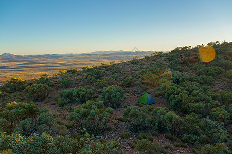 澳洲日出时在山中草地之间的营地内旅游帐篷图片