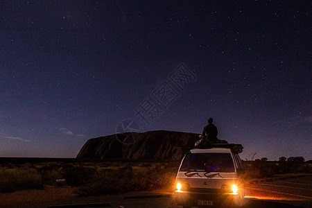 澳州艾尔斯岩乌鲁鲁晚上有车 车上有一个年轻人 澳大利亚红土中心艾尔斯岩背景