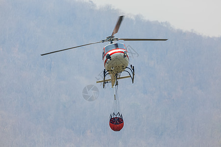 消防直升机携带水桶扑灭森林大火 回湖补水图片