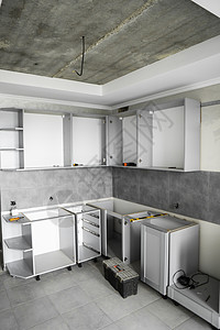 没有家具立面 mdf 的定制厨柜安装 灰色模块化厨房由刨花板材料制成 在厨房的不同安装阶段 地板和墙壁上铺有灰色瓷砖橱柜装修战线背景图片